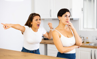 Fototapeta na wymiar Offended scornful young latin american woman listening to angry and dissatisfied female friend, emotionally gesturing and voicing her displeasure. LGBT couple relationship concept..