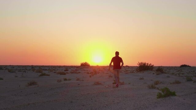 Man walking on sand in safari towards the sunset. Tourist in desert exploring the Chott el Djerid salt lake in Sahara.