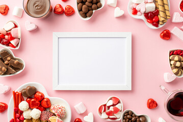 Valentine's Day concept. Top view photo of white photo frame heart shaped plates with sweets candies and glasses with drinking on isolated light pink background with empty space