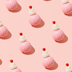 Pastel pink Christmas baubles with cute woolen hats, winter holidays inspired pattern on candy pink background. 