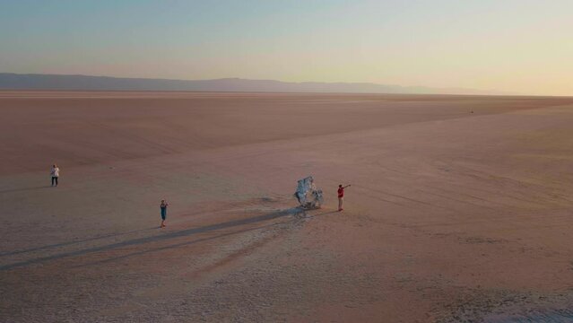 Top shot of tourists aproaching a horse statue to take photos in desert. Man takes pictures of dried Chott el Djerid lake towards a statue.