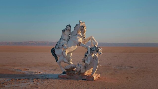 Medium shot of horse and knight statue at the bottom of early existed Chott el Djerid salted lake. Statues in deserted parts of african continent.