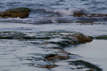 Long exposure of sea and rocks. Waves splashing on the rock creating a beautiful picture. Beautiful colours at sunset.