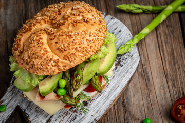 Homemade burger with grilled chicken fillet, asparagus, avocado, tomatoes, peas, cheese and tartar...