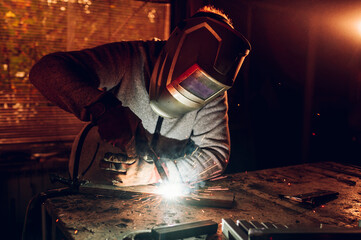Man worker welding metal with welding machine in a factory or workshop