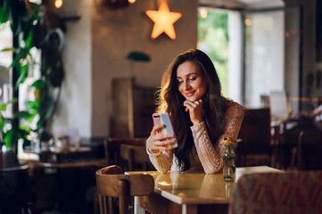 Portrait of beautiful young woman using smartphone in cafeteria