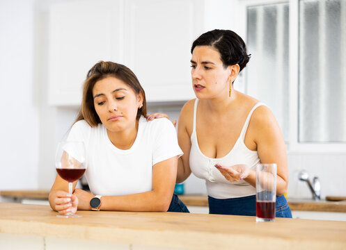 Young woman consoling the depressed woman at table in kitchen