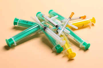 Top view of a pile of medical syringes and insulin syringes with needles at orange background with copy space. Injection treatment concept
