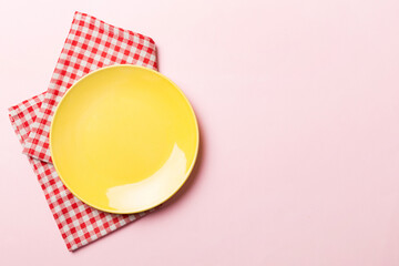 Top view on colored background empty round yellow plate on tablecloth for food. Empty dish on napkin with space for your design