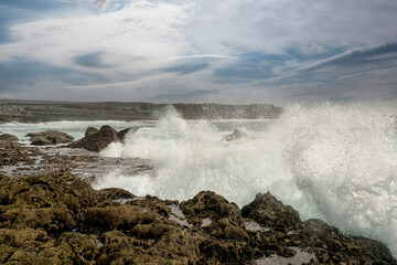 Powerful ocean wave hits rough stone coast of Aran Island, county Galway, Ireland. Rough nature scene. Water splash. Power of nature. Cloudy sky. Irish landscape. Popular tourist area