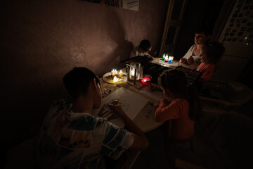 Fototapeta na wymiar Family spending time together during an energy crisis in Europe causing blackouts. Kids drawing in blackout.