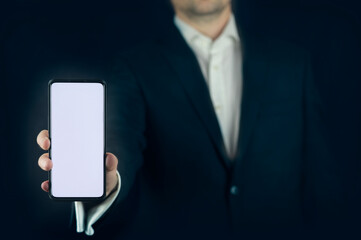 A man (business) holding cell phone (mobile phone). Free (blank) white space to use. Telly screen (mockup). All with dark blue background. Ideally for business presentations.  - obrazy, fototapety, plakaty