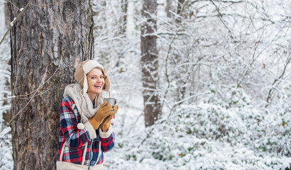 Girl enjoy mulled wine. woman in mittens drinking tea in snowy forest. outdoors on frosty day. travel and hiking. girl hiker drink cup of hot tea. warm yourself up. woman winter drink. copy space