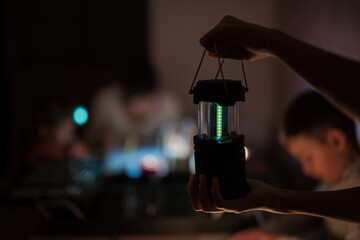 Family spending time together during an energy crisis in Europe causing blackouts. Led lantern in...