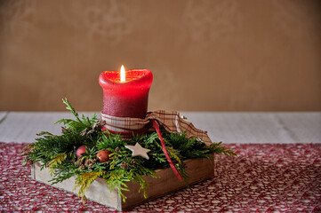 Dekoratives Adventsgesteck mit brennender roter Kerze