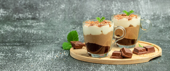 dessert three chocolates pudding decorated with mint on a light background. Layered delicious dessert. Long banner format