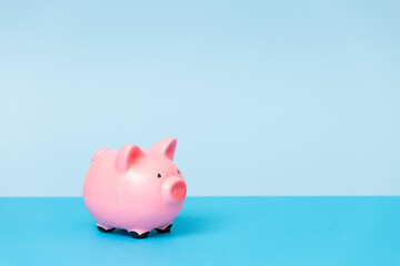  Pink piggy bank on a blue background. The concept of investment in real estate, into the future, savings, financial planning.Copy space
