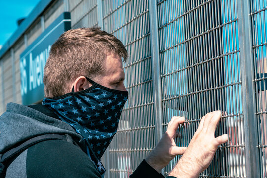 person in a mask holding on to a fence