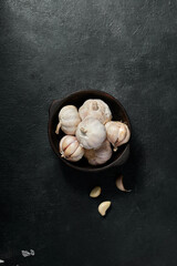 Whole garlic in the peel, organic product, garlic cloves on a rustic table in a bowl.