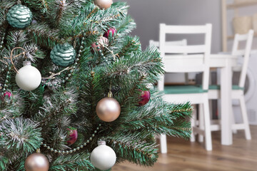 Christmas tree in the kitchen-living room with white chairs in the background, New Year's atmosphere of comfort