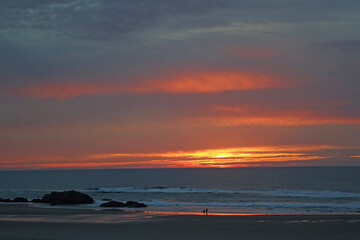Fototapeta premium Sunset Walkers - The beach is a favorite for a casual walk at day's end