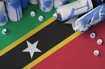 Saint Kitts and Nevis flag and few used aerosol spray cans for graffiti painting. Street art...