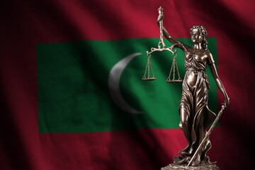 Maldives flag with statue of lady justice and judicial scales in dark room. Concept of judgement...