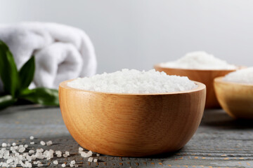 Fototapeta na wymiar Bowls of natural sea salt on grey wooden table, closeup