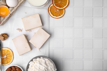 Yeast and ingredients for dough on white tiled table, flat lay. Space for text