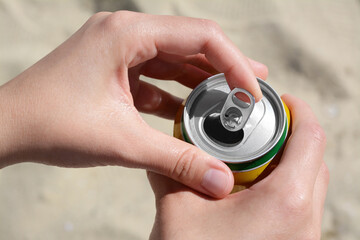 Woman opening can with sparkling drink at beach, closeup