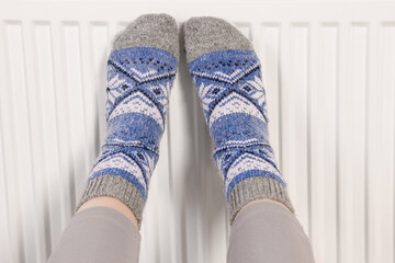 Woman warming feet near heating radiator, closeup