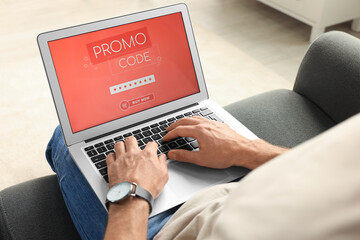 Man holding laptop with activated promo code on sofa, closeup