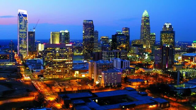 Aerial Backward Shot Of Illuminated Downtown In Residential City Against Cloudy Sky At Dusk - Charlotte, North Carolina