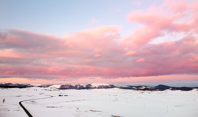Picturesque drone view of the sunset over a snow covered mountain valley. Winter landscape from a bird's-eye view.