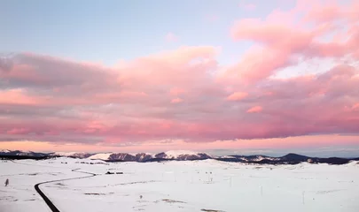 Selbstklebende Fototapeten Hellrosa Picturesque drone view of the sunset over a snow covered mountain valley. Winter landscape from a bird's-eye view.  © Maria Sbytova