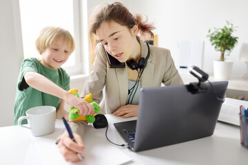 Young woman working online using laptop at home. Home office and parenthood at same time. Exhausted...