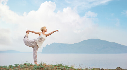 Senior woman doing yoga exercises with mountain and sky on the background - Powered by Adobe