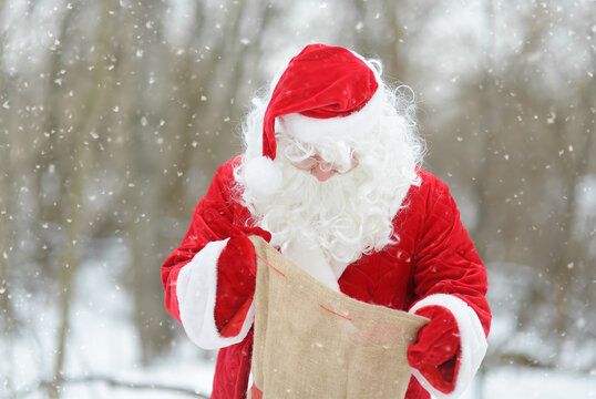 Santa Claus takes Christmas presents out of the bag. An animator or a parent in a Santa Claus costume at a holiday for children. St. Nicholas Day.
