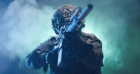 Soldier fully equipped with tactical gear and protection aiming his rifle at enemy with blue and green smoke in the background.