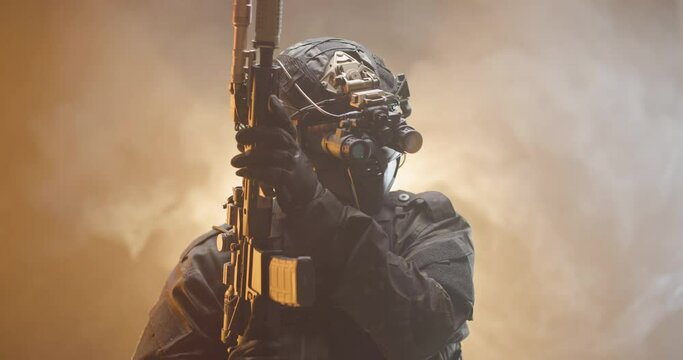 Soldier fully equipped with tactical gear and protection aiming his rifle at enemy with orange smoke in the background.