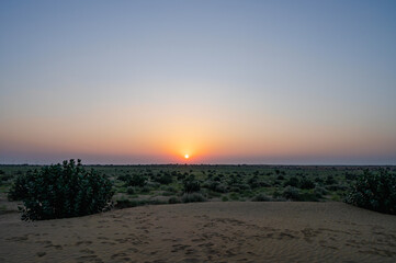 Fototapeta na wymiar Sun rising at the horizon of Thar desert, Rajasthan, India. Tourists from across India visits to watch desert sun rise at Thar desert.