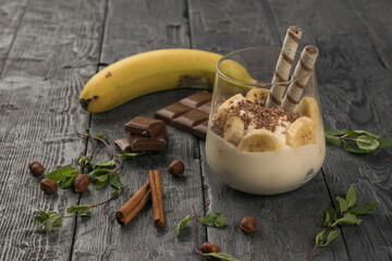 Banana dessert with chocolate cinnamon and nuts on a wooden table.