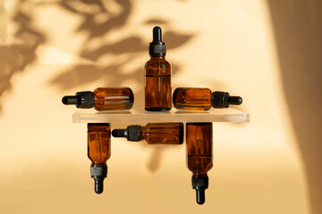 Composition of amber bottles with cosmetic serum on beige background in rays of sunlight. Mockups...