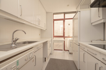 kitchen with white wood cabinets with matching countertops, built-in appliances and matching white walls