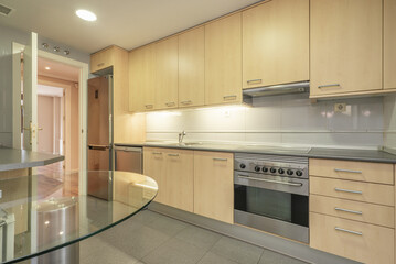 Wall of a kitchen covered with base and wall units made of beech wood combined with stainless steel...