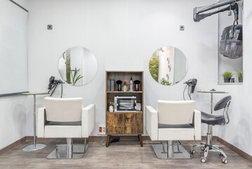 Twin white leatherette sofas in a beauty salon with circular mirrors on the wall