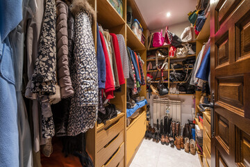 walk-in closet with wooden shelves, drawers and full of clothes on the hangers