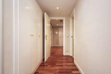 Distributor corridor of a house full of cabinets with white doors and reddish wooden parquet floors