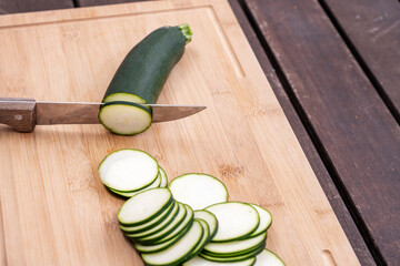 Cut a raw zucchini with a sharp knife and stack many thin slices on a bamboo board