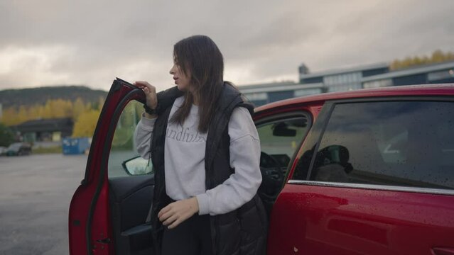 Woman exiting a car to charge her electric vehicle.